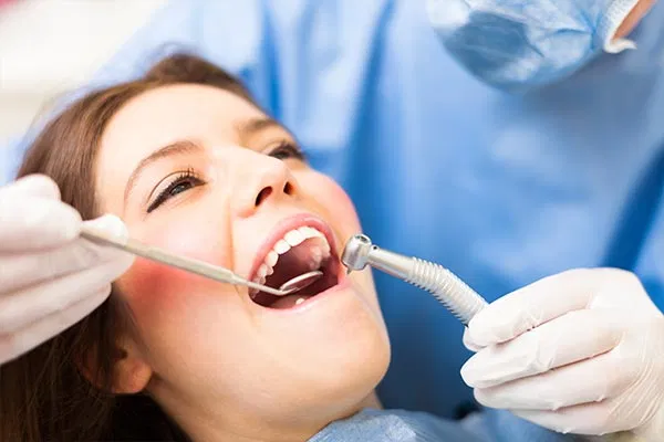 A patient receiving a gentle dental checkup in a bright, modern clinic. The dental professional is using a mirror and modern equipment, illustrating the high-quality care available at Salt Flats Dentistry.