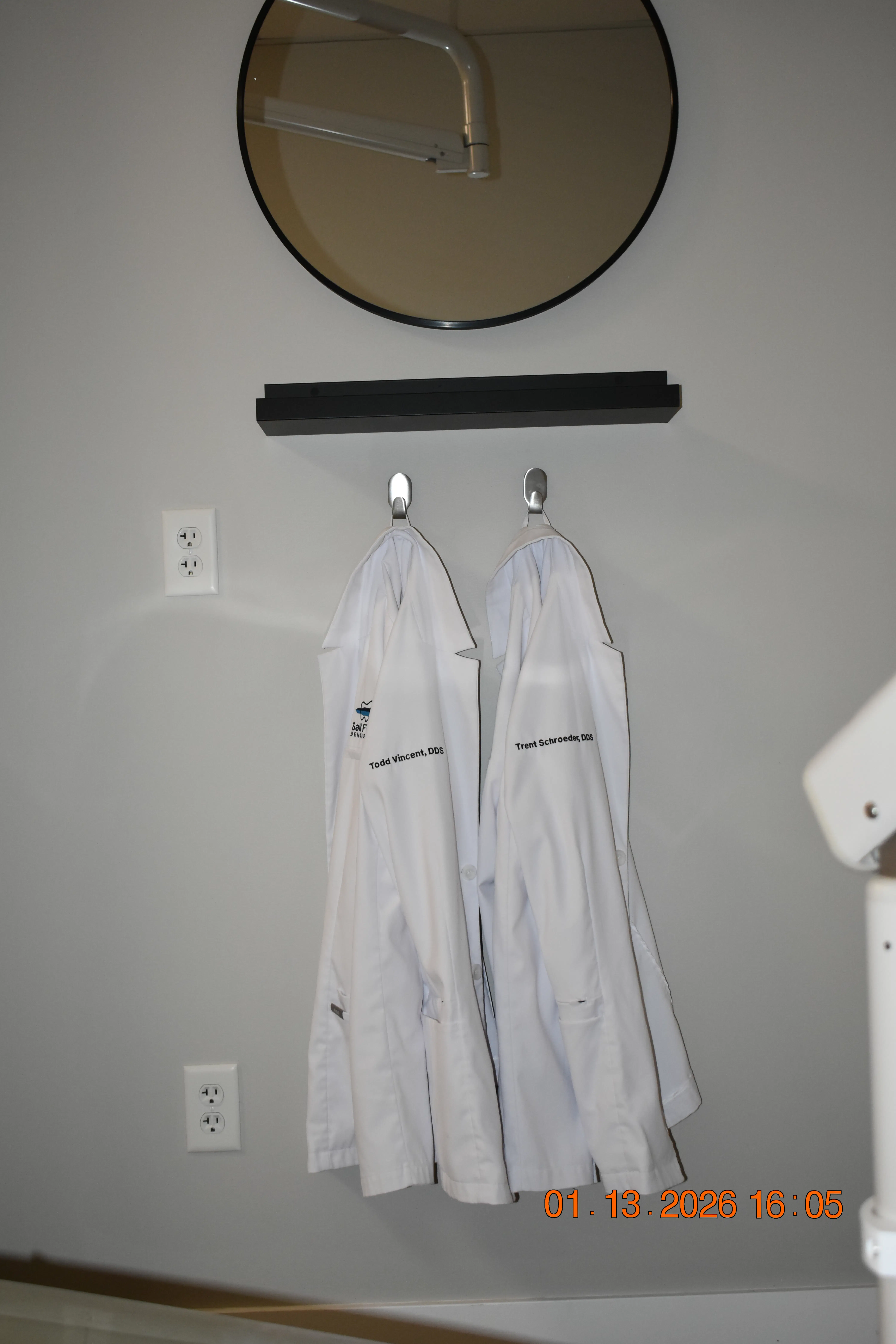 Two Salt Flats Dentistry doctor coats, labeled for Dr. Todd Vincent, DDS and Dr. Trent Schroeder, DDS, hanging in a clean, welcoming environment.